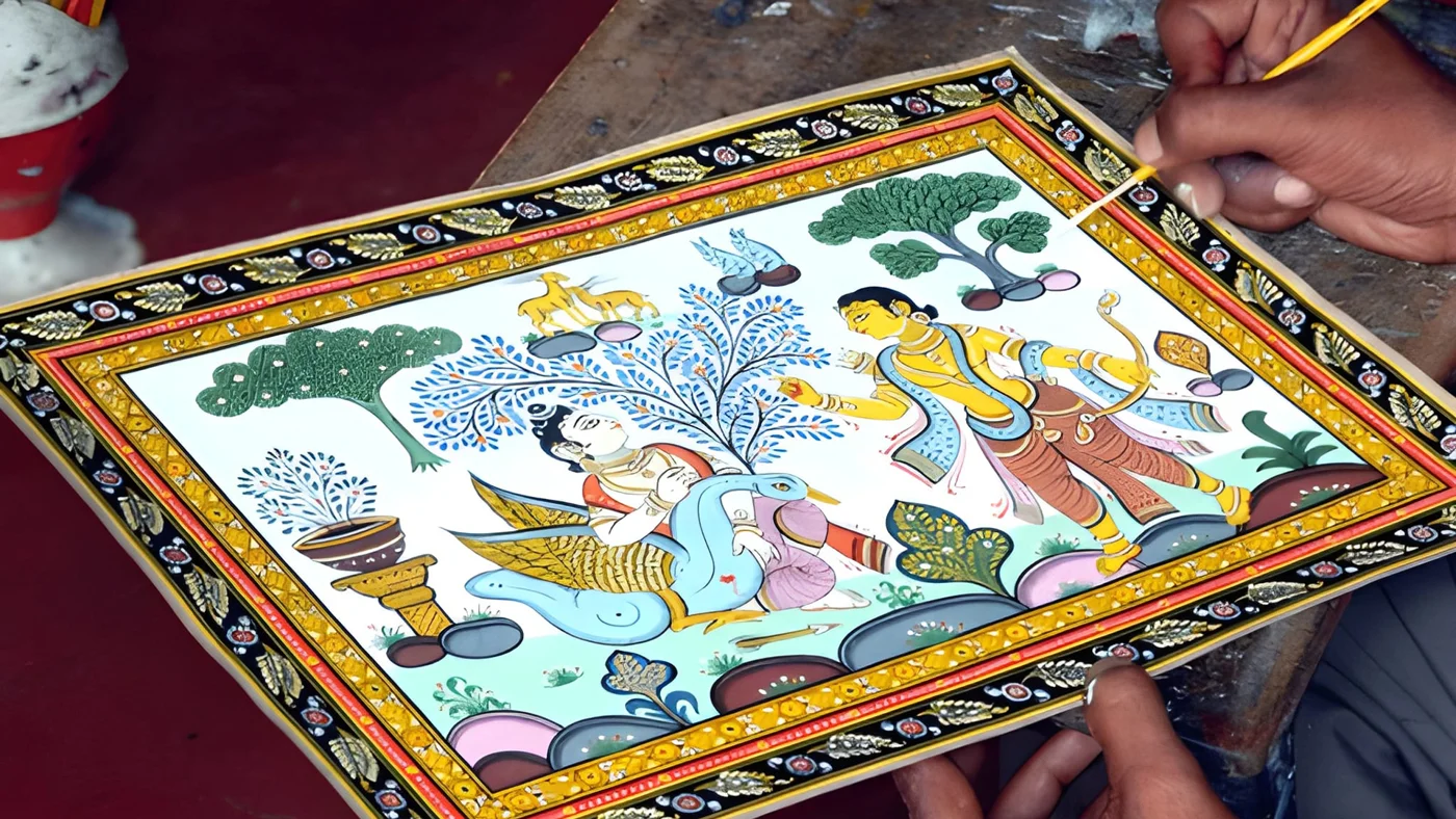 An artisan holding a detailed Pattachitra painting